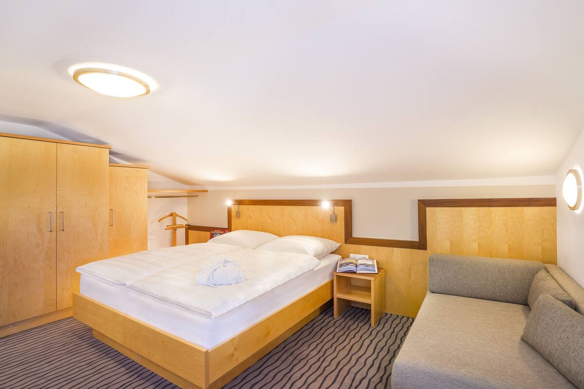 Une chambre d’hôtel équipée d’un lit, d’un canapé, d’une armoire et d’une lampe de lecture.