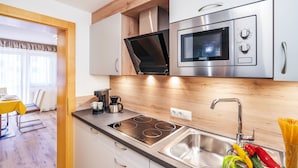 A modern kitchen with a built-in oven, microwave, and stovetop. - Aliona Apart (Soelden)