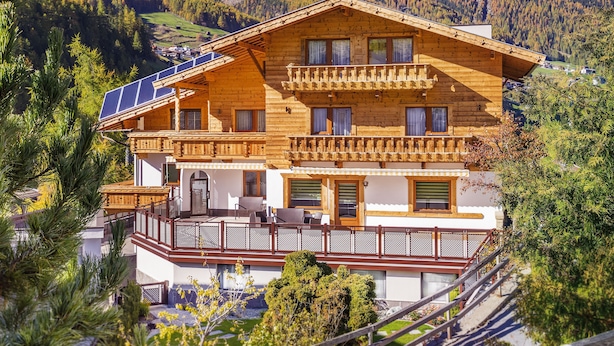 A chalet with a balcony, solar panels, and a mountain backdrop. - Aliona Apart (Soelden)