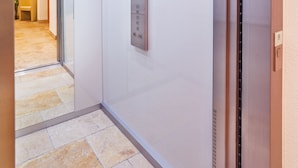 A modern elevator with a metallic finish and a control panel with buttons. - Aliona Apart (Soelden)