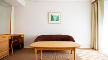 A room with a wooden desk, a brown sofa, and a framed picture on the wall.