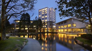 A modern hotel with a reflective pool, a well-maintained garden, and a prominent building with multiple floors and balconies. - Mars Garden Wood Gotemba (Gotemba)