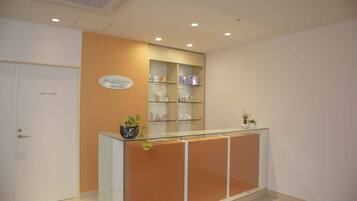 A reception area with a glass counter, shelves with toiletries, and a sign above the counter.