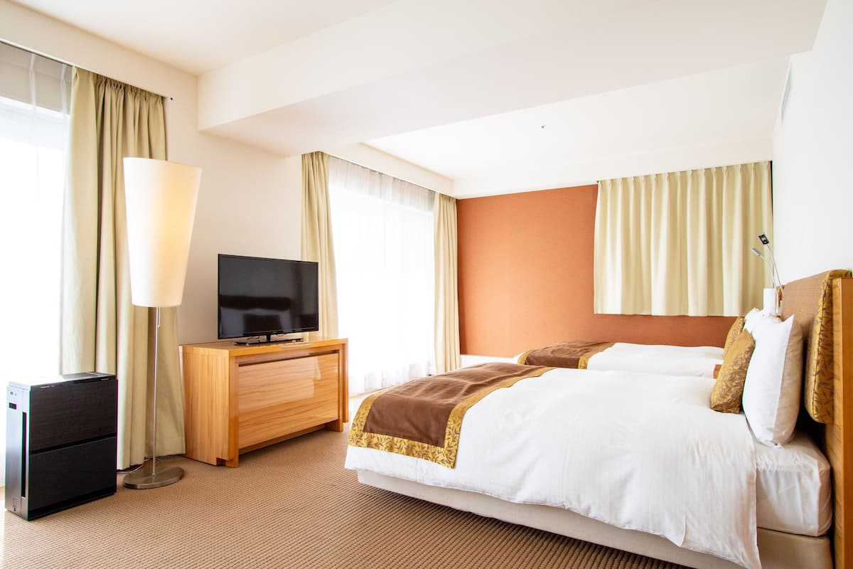 Una habitación de hotel con una cama, un televisor, un escritorio y una lámpara.