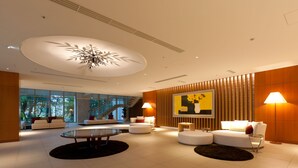 A modern lobby with a central seating area, a staircase, and a large painting on the wall. - Mars Garden Wood Gotemba (Gotemba)
