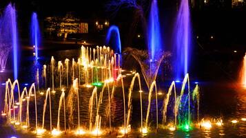 Vista nocturna de un espectáculo de fuentes de agua con múltiples chorros iluminados en varios colores.
