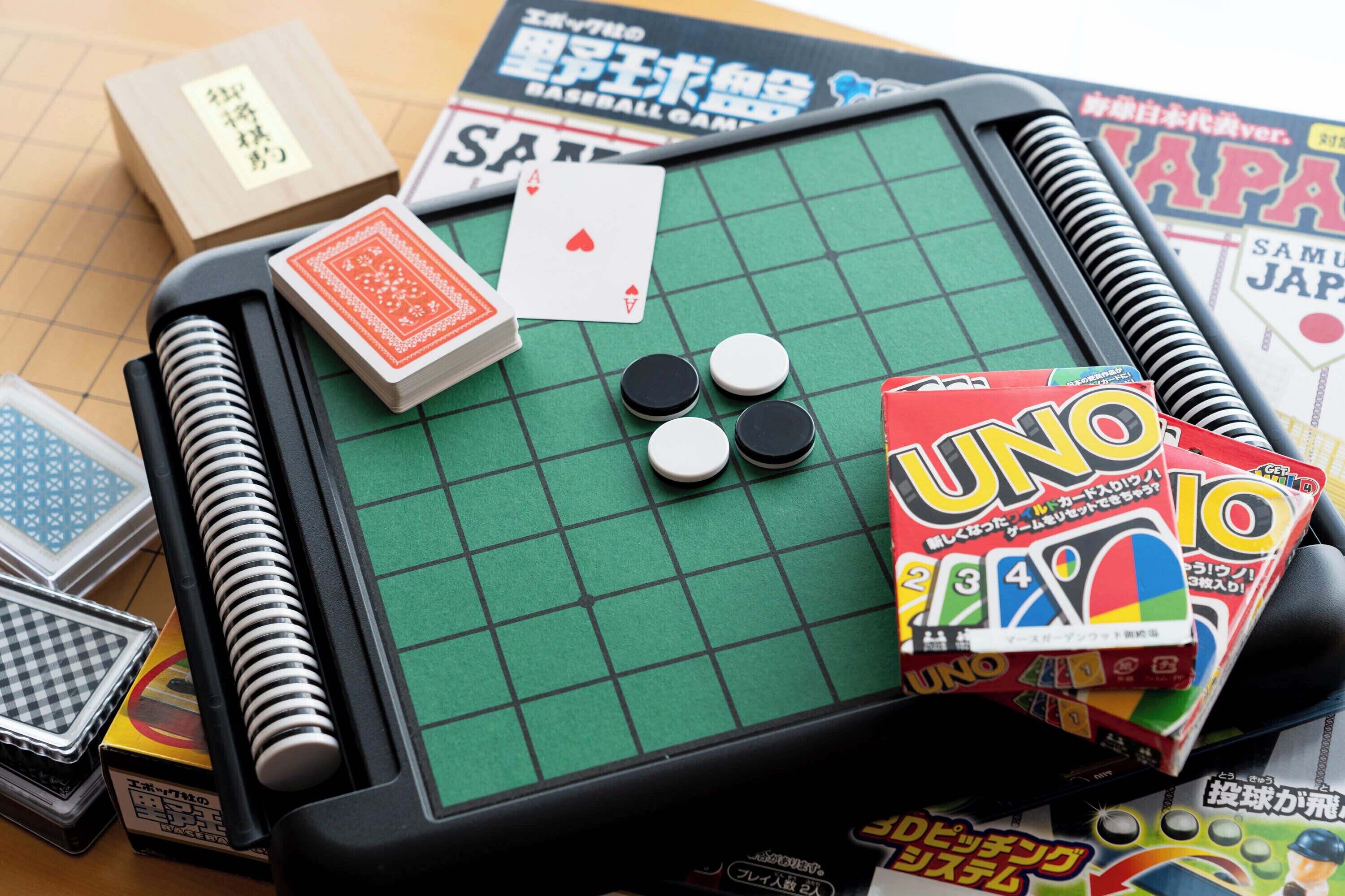 A checkered game table with playing cards, poker chips, and UNO cards.