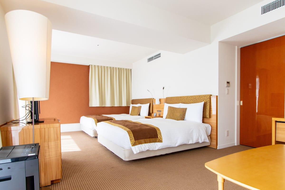 Una habitación de hotel con una cama grande, un escritorio, una lámpara y una puerta de madera.