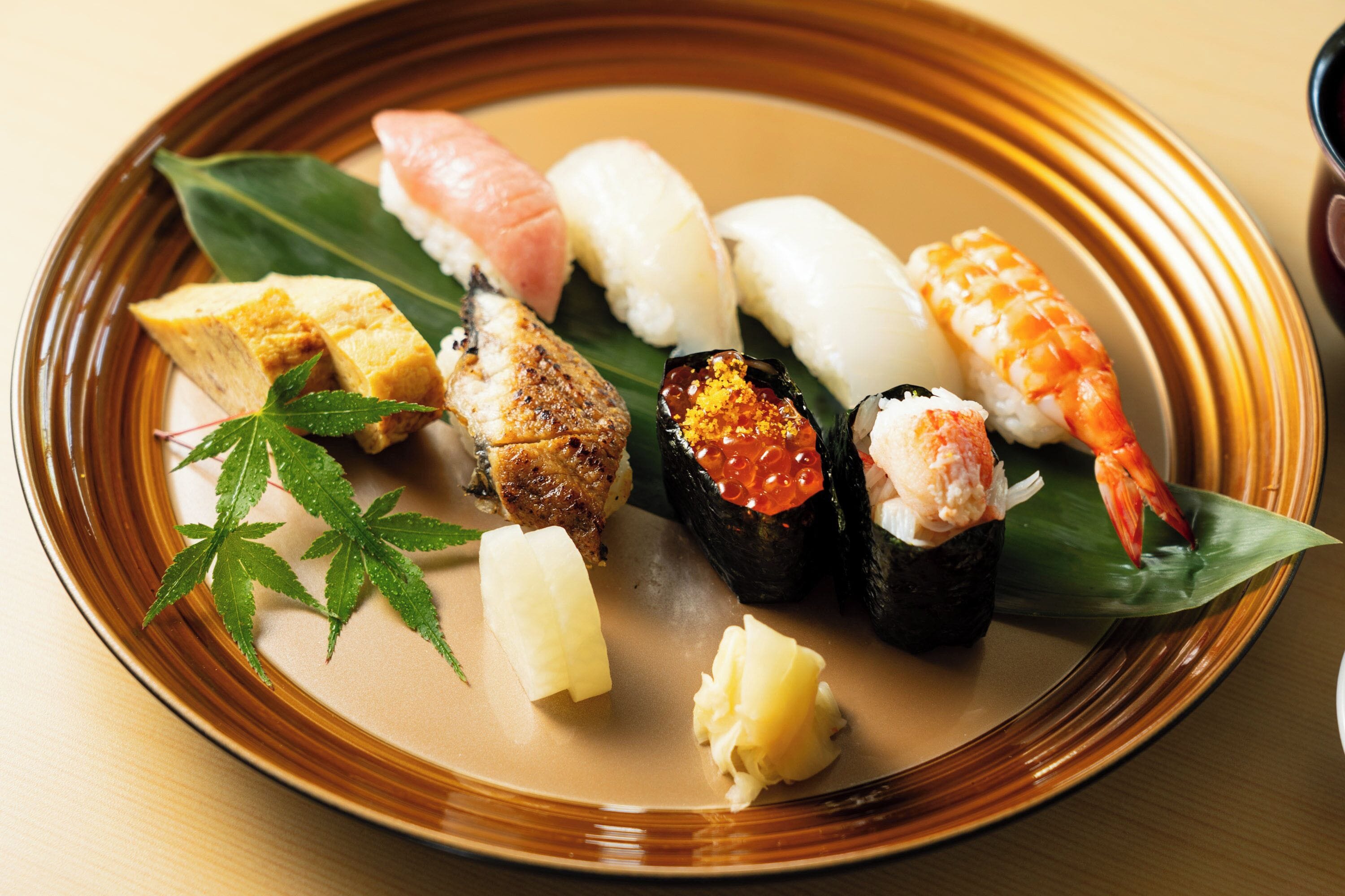 A plate of sushi with various types including nigiri and sashimi, garnished with wasabi and pickled ginger.