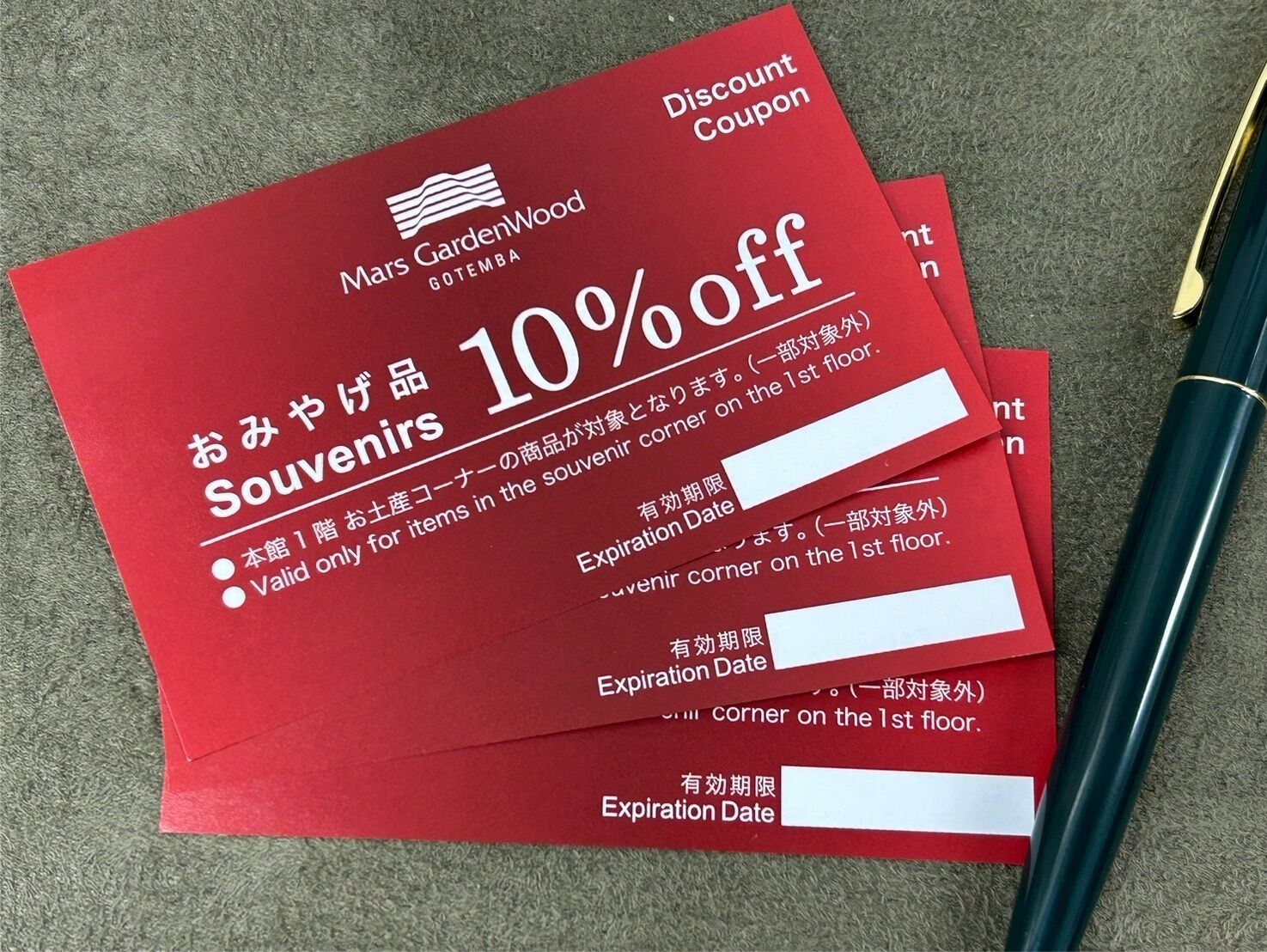 A stack of red souvenir coupon cards with a 10% discount offer from Mars GardenWood Gotemba.