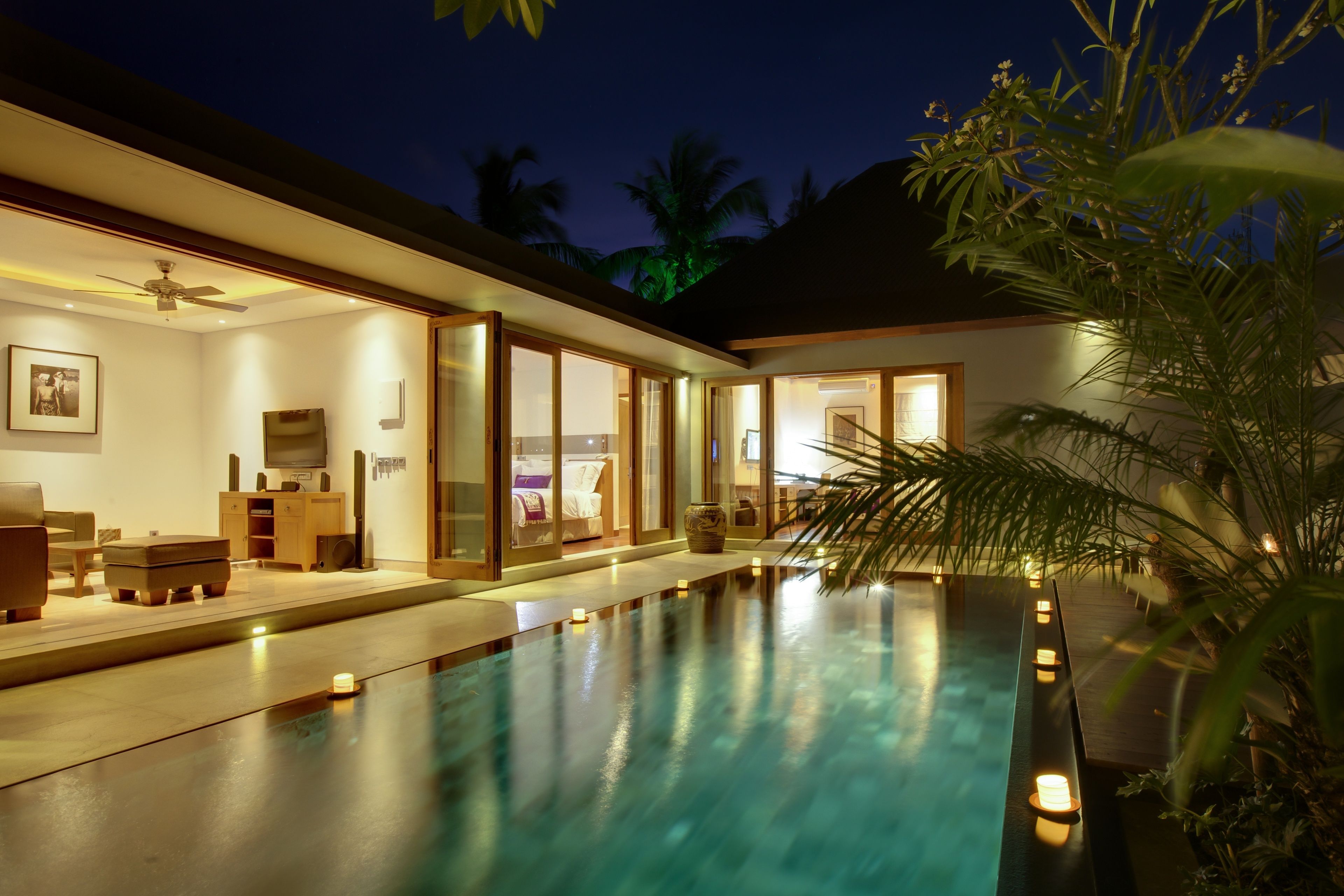 Une maison moderne dotée d’une piscine, de grandes fenêtres et d’un ventilateur de plafond.
