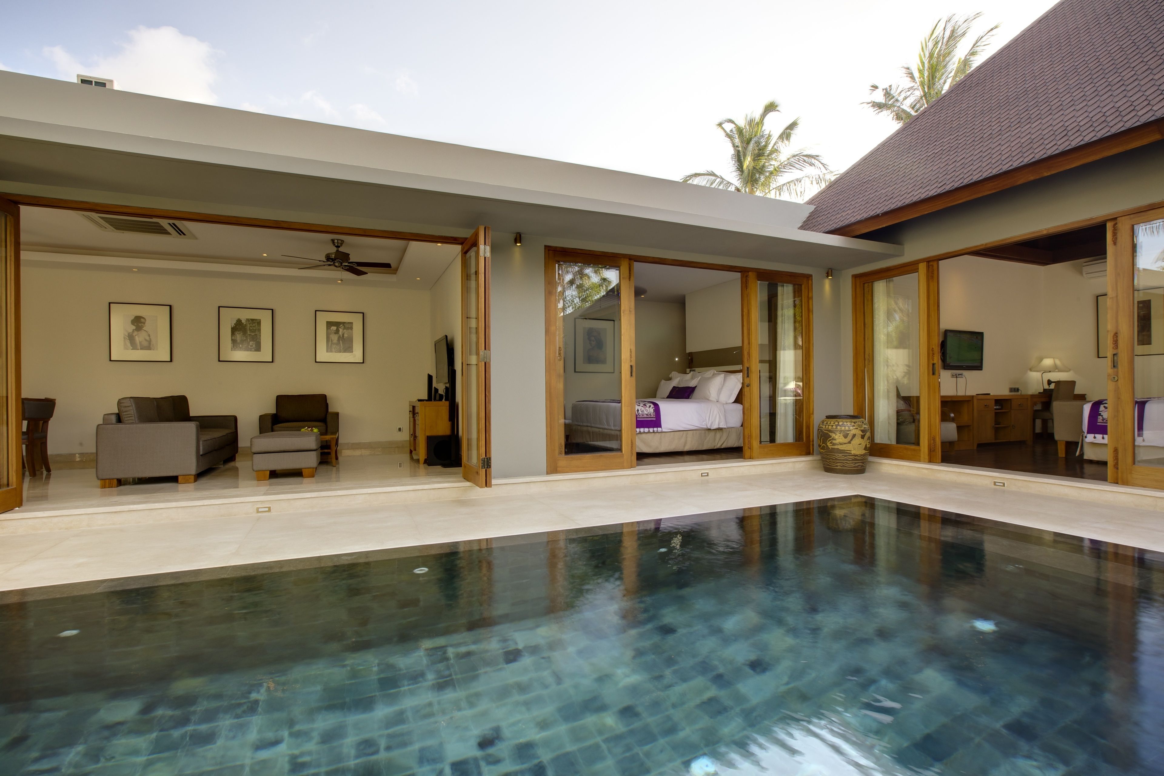 A modern indoor swimming pool with a clear view of the adjacent bedroom and living area.
