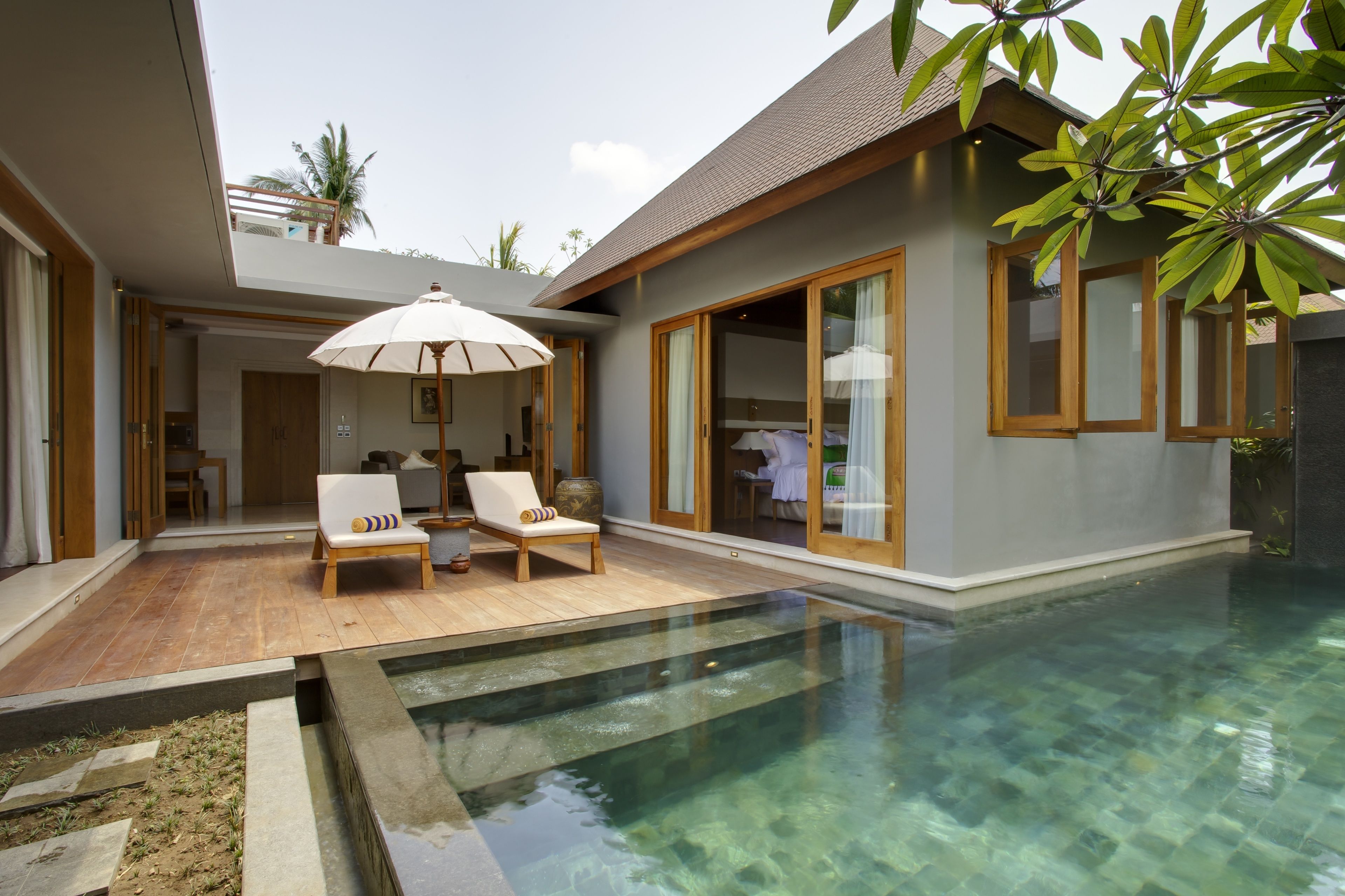 Une maison moderne dotée d’une piscine, d’une terrasse en bois et d’un grand parasol.