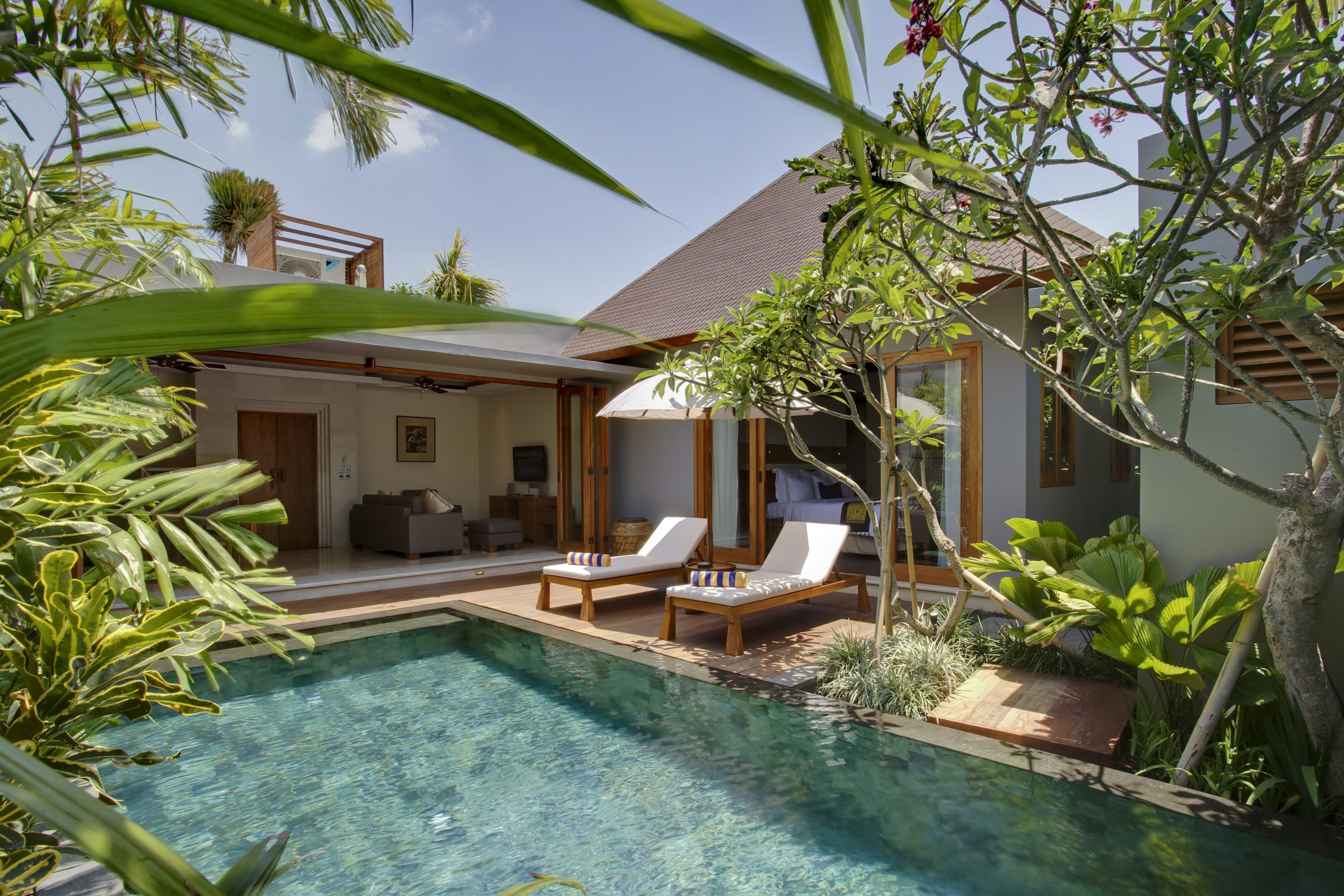 Ein modernes Haus mit Swimmingpool, Liegestühlen und einer überdachten Terrasse.