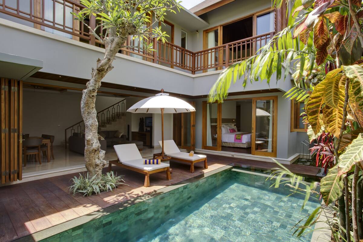 A modern house with a swimming pool, wooden deck, and a balcony with a view of the pool.