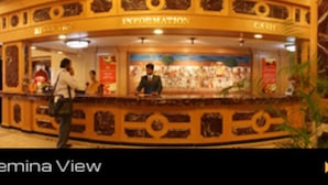 A lobby with a curved reception desk labeled "INFORMATION" and "CASH." - Hotel Femina (Tiruchirappalli)