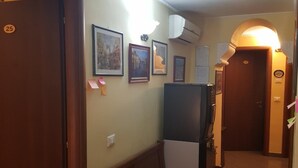 Un couloir avec un banc en bois, des tableaux encadrés accrochés au mur et une porte portant le numéro 25.