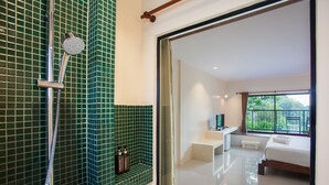 A hotel room with a shower, a bed, a bedside table, and a view of the outdoors. - Lima Bella Resort (Rayong)