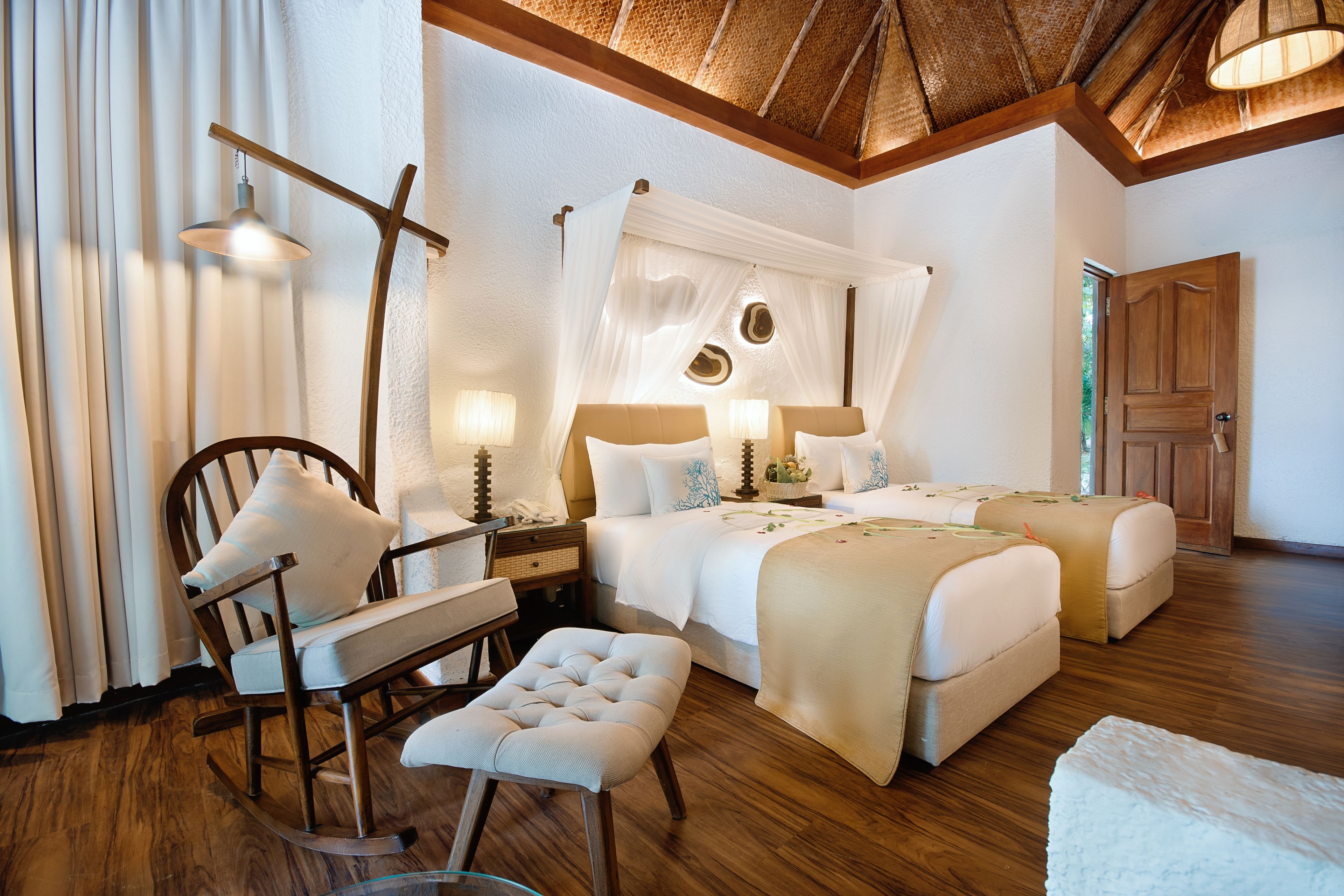A spacious bedroom with a large bed, two bedside tables, a chair, and a bench.