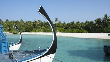 Un bote amarrado en una playa con agua turquesa cristalina y palmeras al fondo.