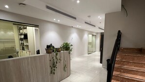 A modern reception area with a marble counter, potted plants, and a staircase with a black handrail. - Jerusalem Metropole Hotel (Jerusalem)