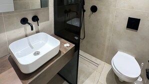A modern bathroom with a white sink, a glass-enclosed shower, and a toilet. - Jerusalem Metropole Hotel (Jerusalem)