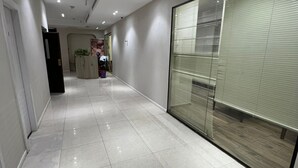 A clean, modern hallway with a shiny tiled floor, recessed lighting, and a glass partition on one side. - Jerusalem Metropole Hotel (Jerusalem)