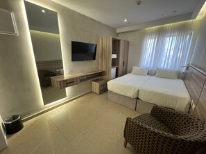 A modern hotel room with a large bed, a TV mounted on the wall, a seating area with a chair, and a wardrobe. - Jerusalem Metropole Hotel (Jerusalem)