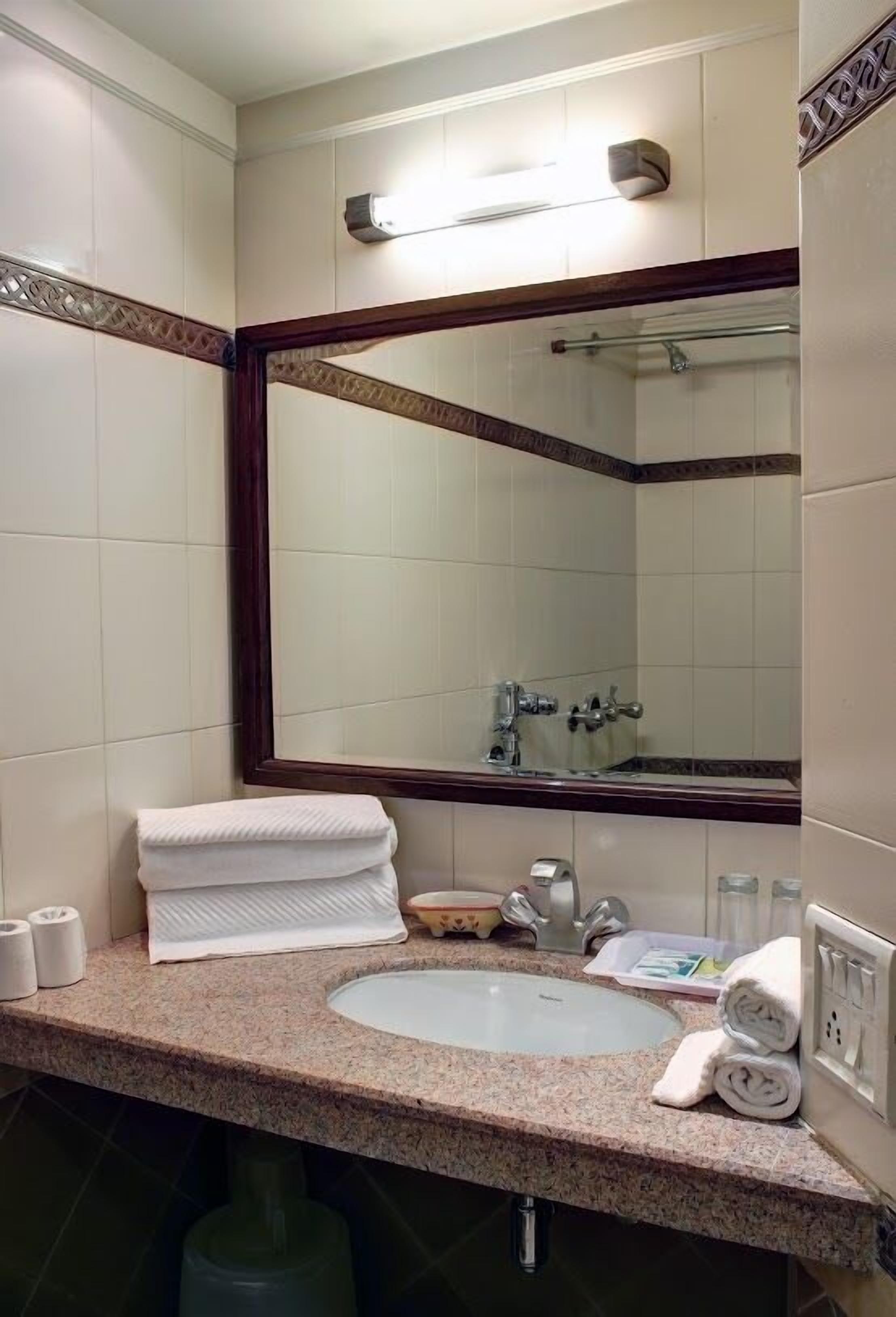 Un baño con un espejo grande, un lavabo y un inodoro.