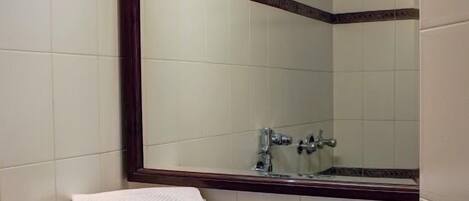 Un baño con un espejo grande, un lavabo y un inodoro.