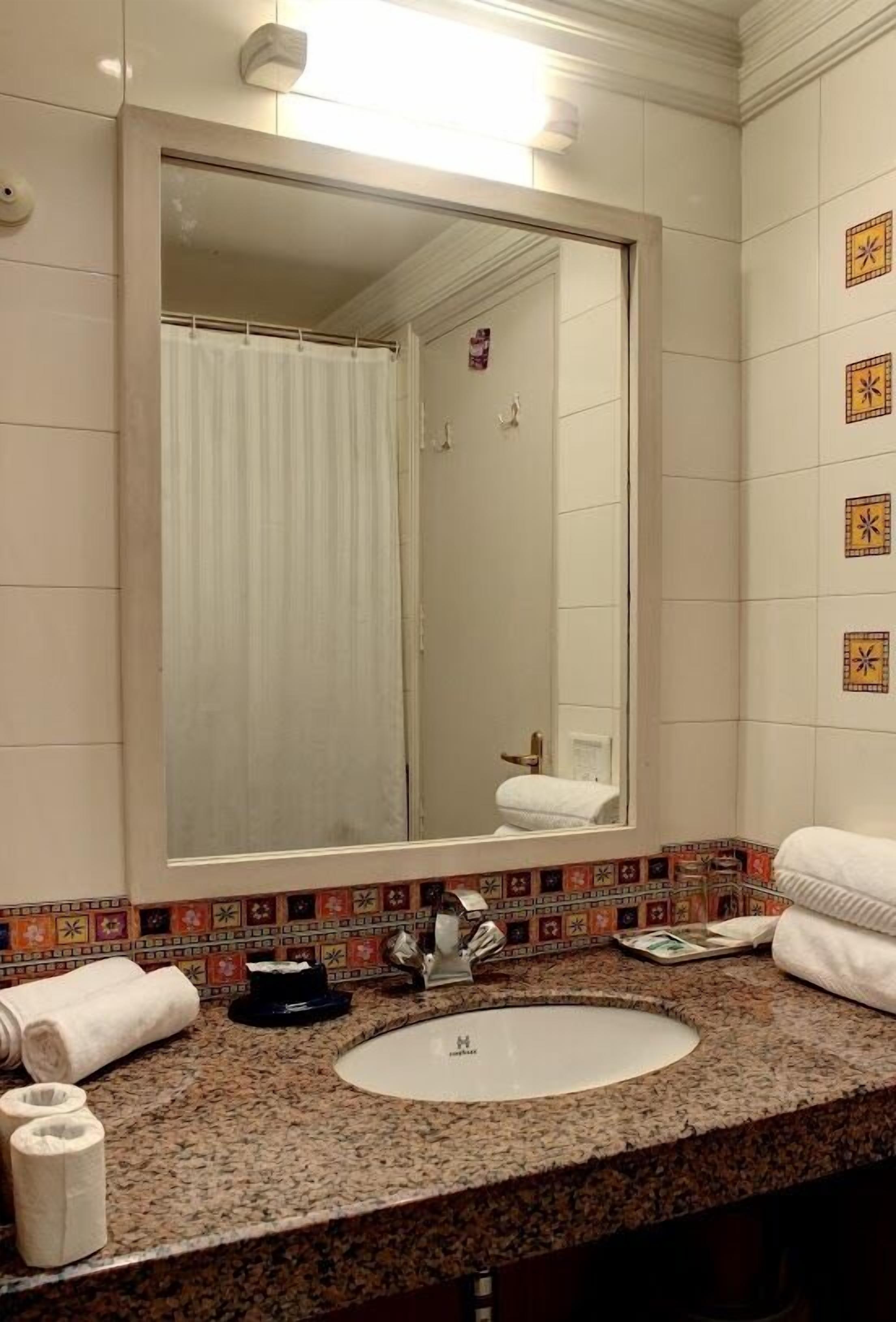 A bathroom with a large mirror, a sink, and a shower.