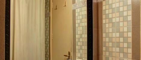 Une salle de bain avec un grand miroir, un lavabo et un porte-serviettes.