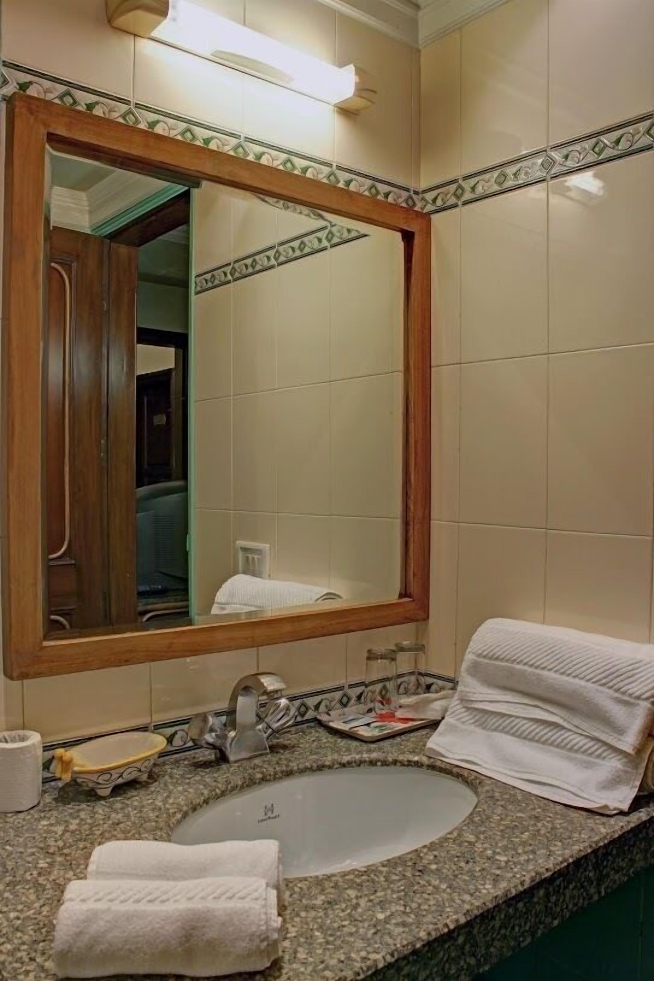 Une salle de bain avec un grand miroir, un lavabo et un porte-serviettes.