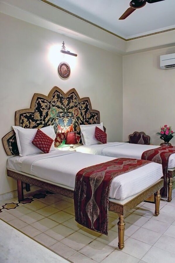 A double bed with a decorative headboard, a bedside table with a vase of flowers, and a ceiling fan.