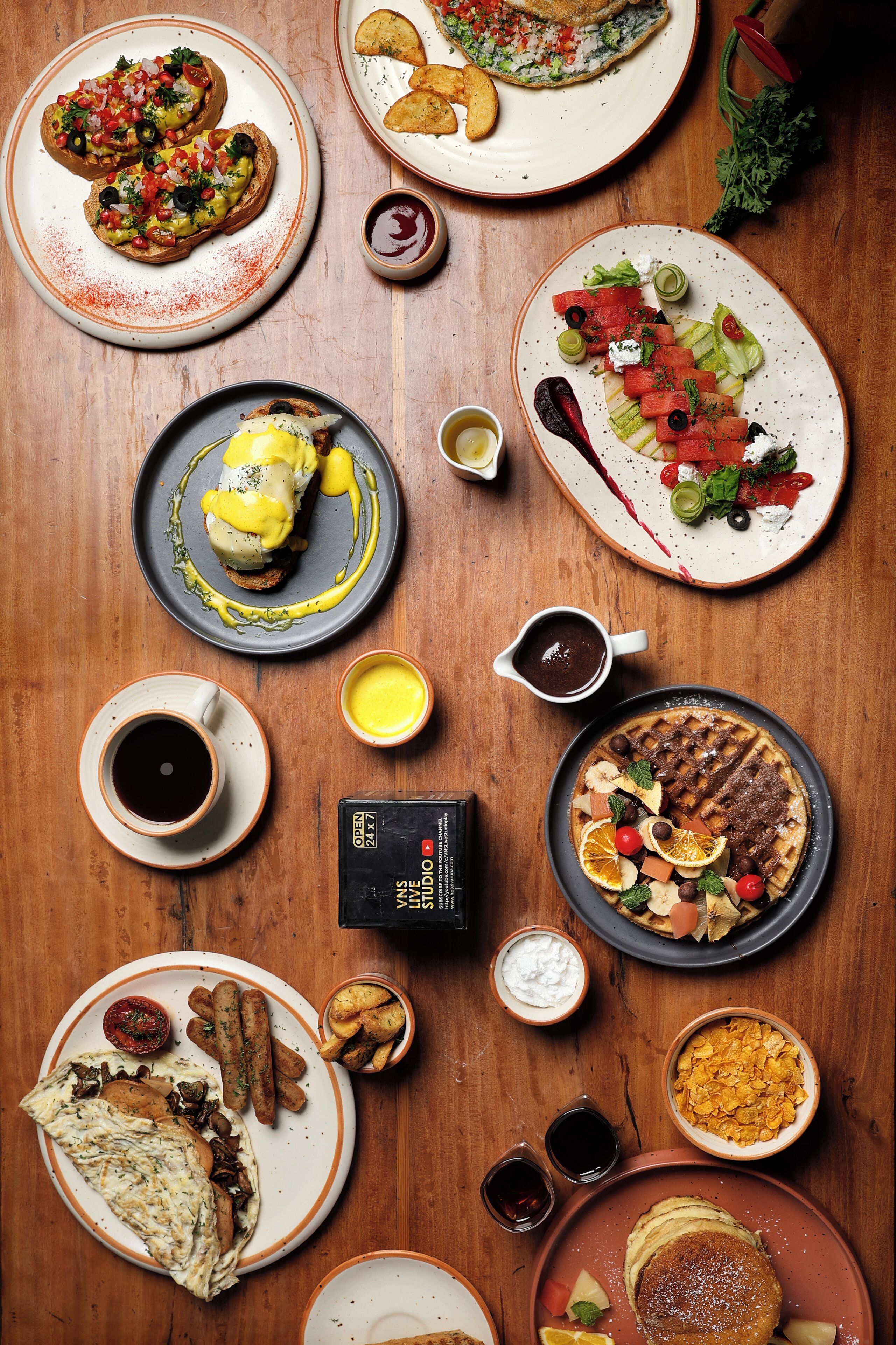 A variety of breakfast dishes on a wooden table, including eggs, toast, and pancakes.