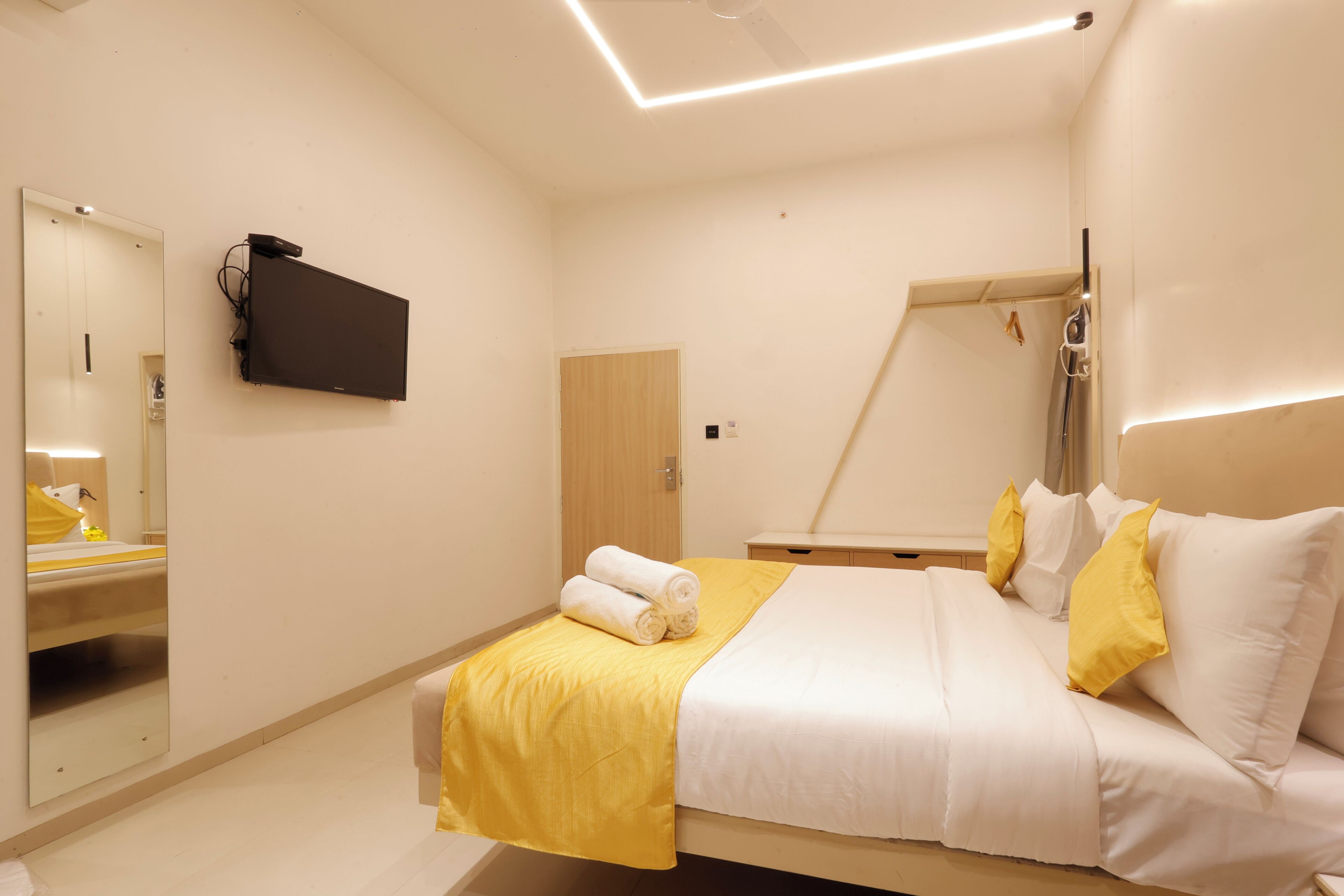 Une chambre d’hôtel équipée d’un lit, d’une télévision, d’un miroir et d’un espace douche.