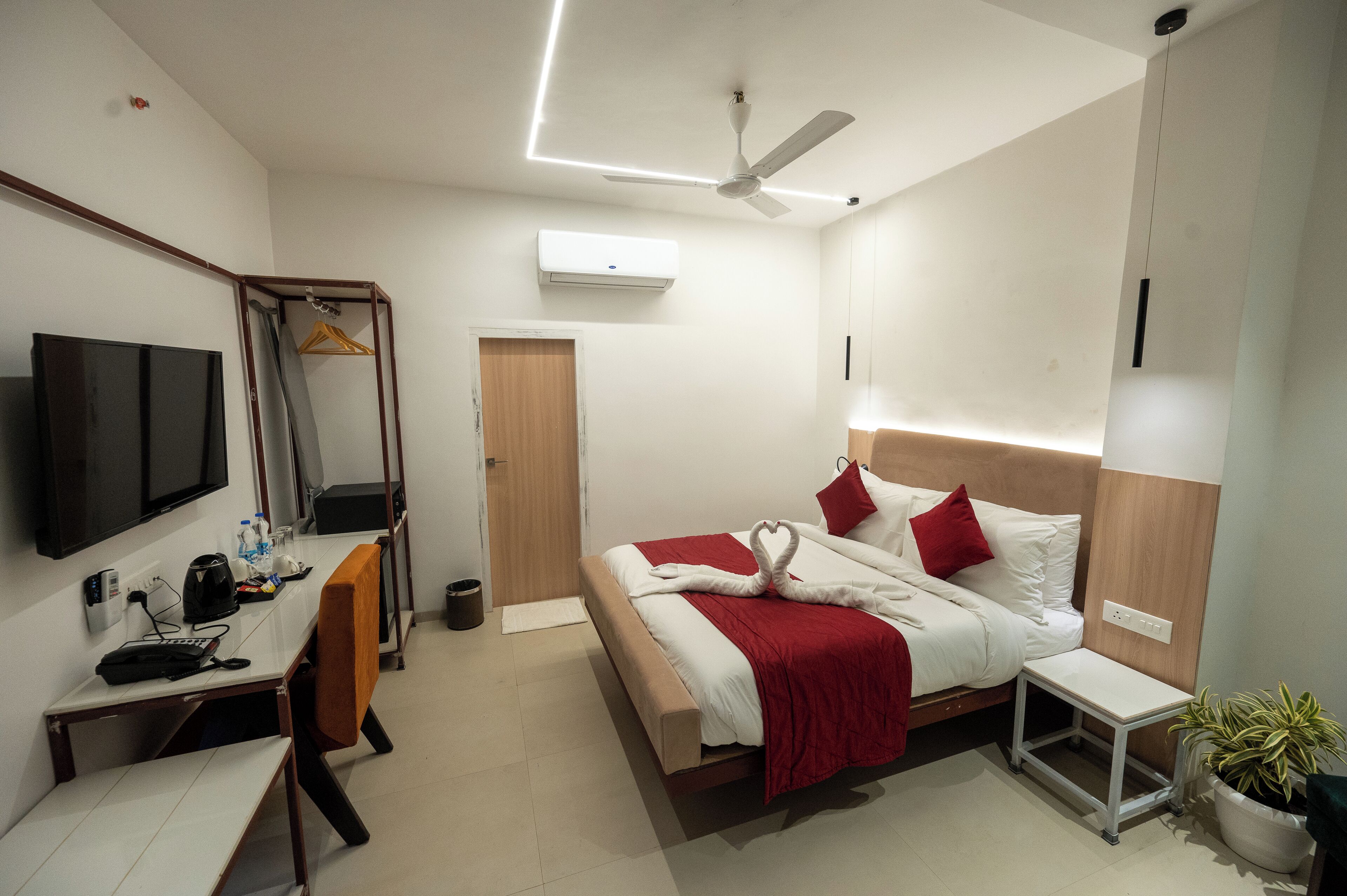Une chambre d’hôtel équipée d’un lit, d’une table de chevet, d’une chaise, d’un bureau, d’une télévision et d’un appareil de climatisation.
