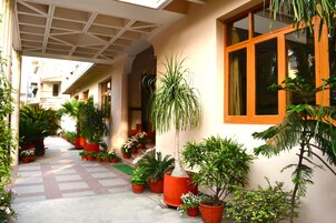 A covered walkway with potted plants and a building with large windows.