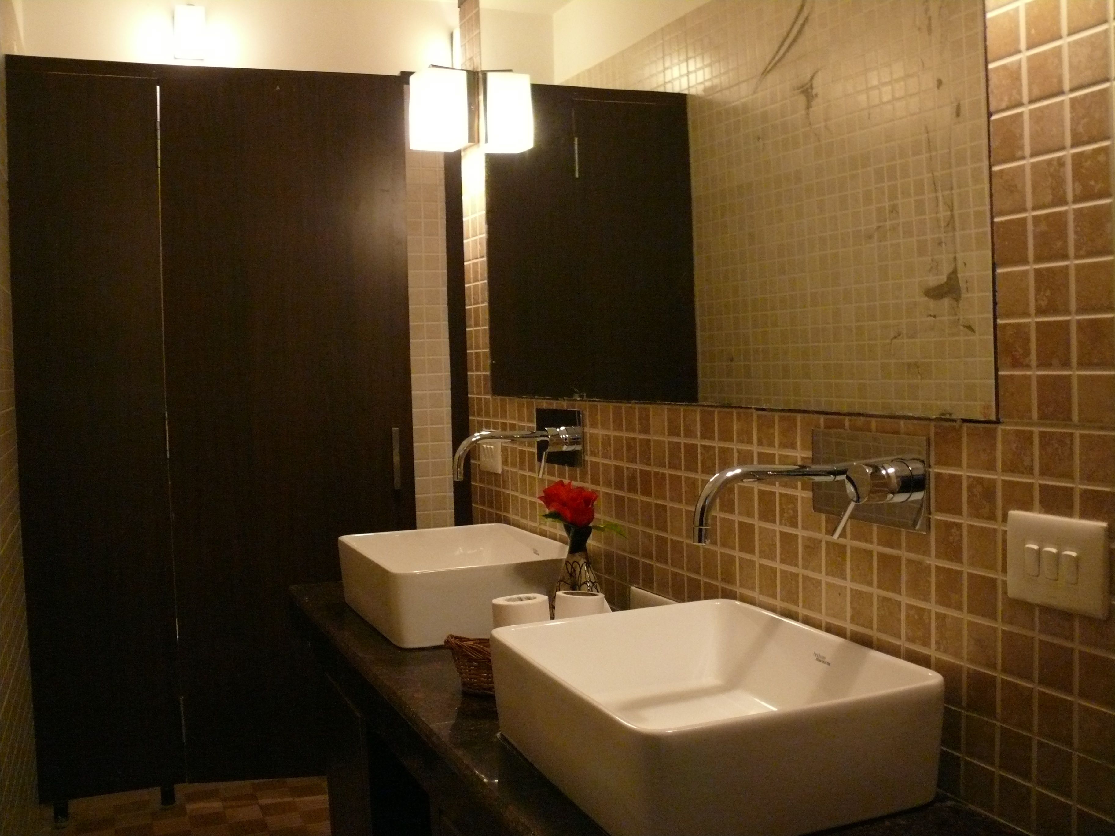 Un bagno con due lavandini, uno specchio e un mobile contenitore in legno scuro.