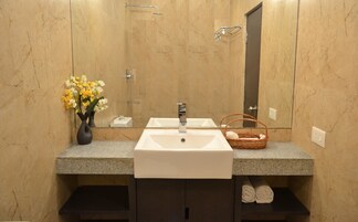 A bathroom with a marble vanity, a white sink, a mirror, a towel rack, and a wicker basket.