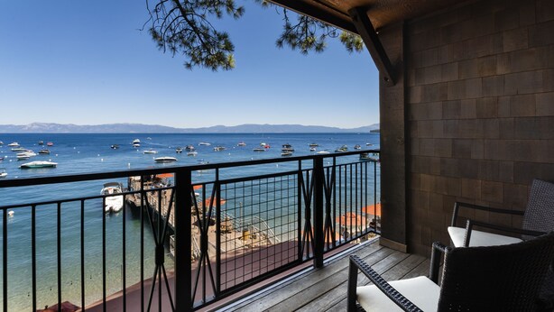 Un balcon avec vue sur la mer et les bateaux, un plancher en bois et des rampes en métal.