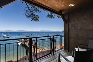 Un balcon avec vue sur la mer et les bateaux, un plancher en bois et des rampes en métal.