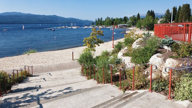 A coastal walkway leading to a beach with boats in the water and mountains in the background. - WorldMark McCall (McCall)
