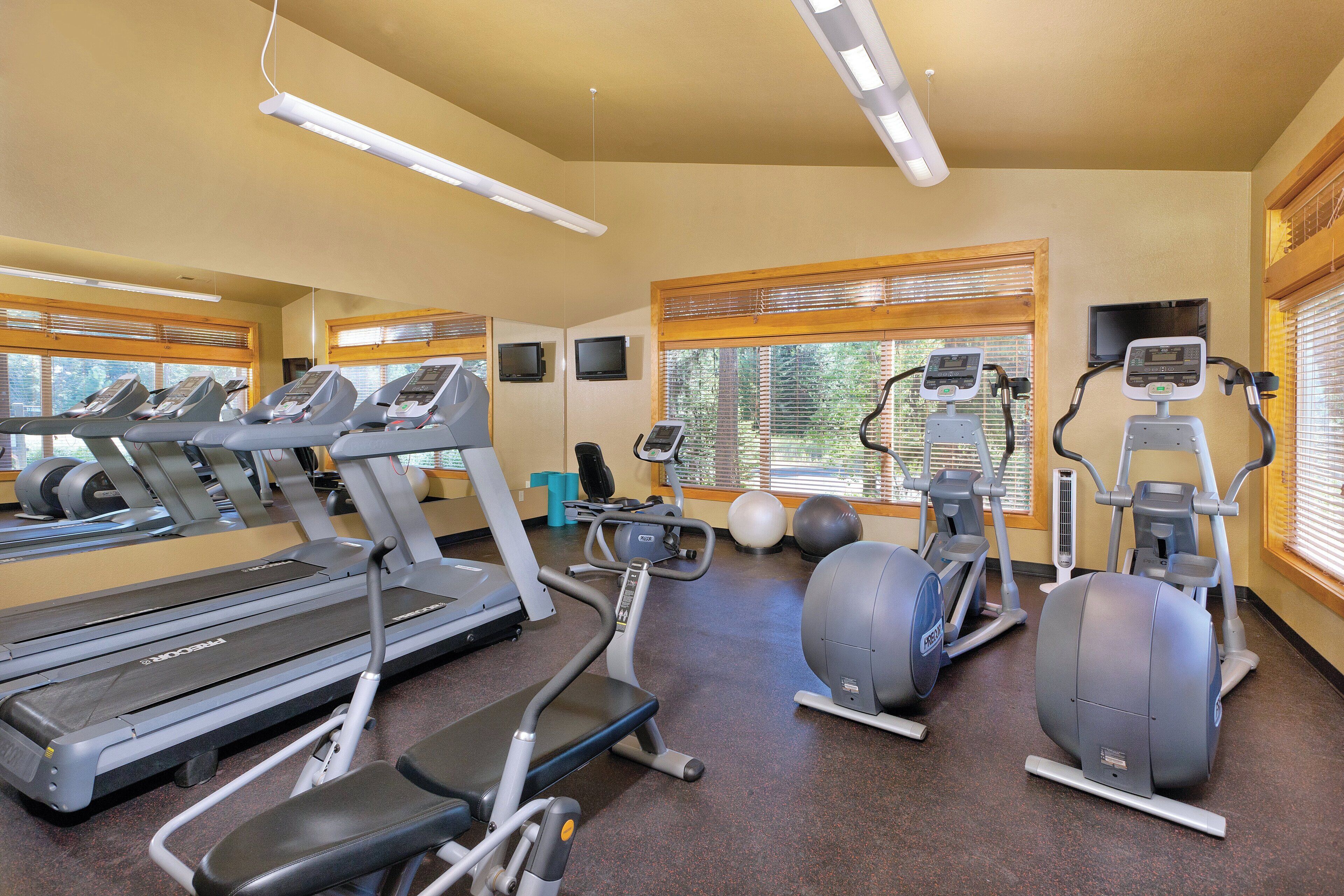 A gym with treadmills, elliptical machines, and exercise balls.