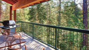 A wooden deck with a grill and chairs overlooking a forest. - WorldMark McCall (McCall)