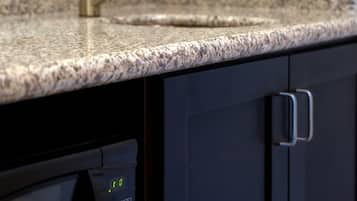 A kitchen with a granite countertop, a stainless steel sink, and a microwave.