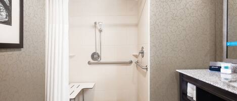 A bathroom with a shower, a sink, and a mirror.