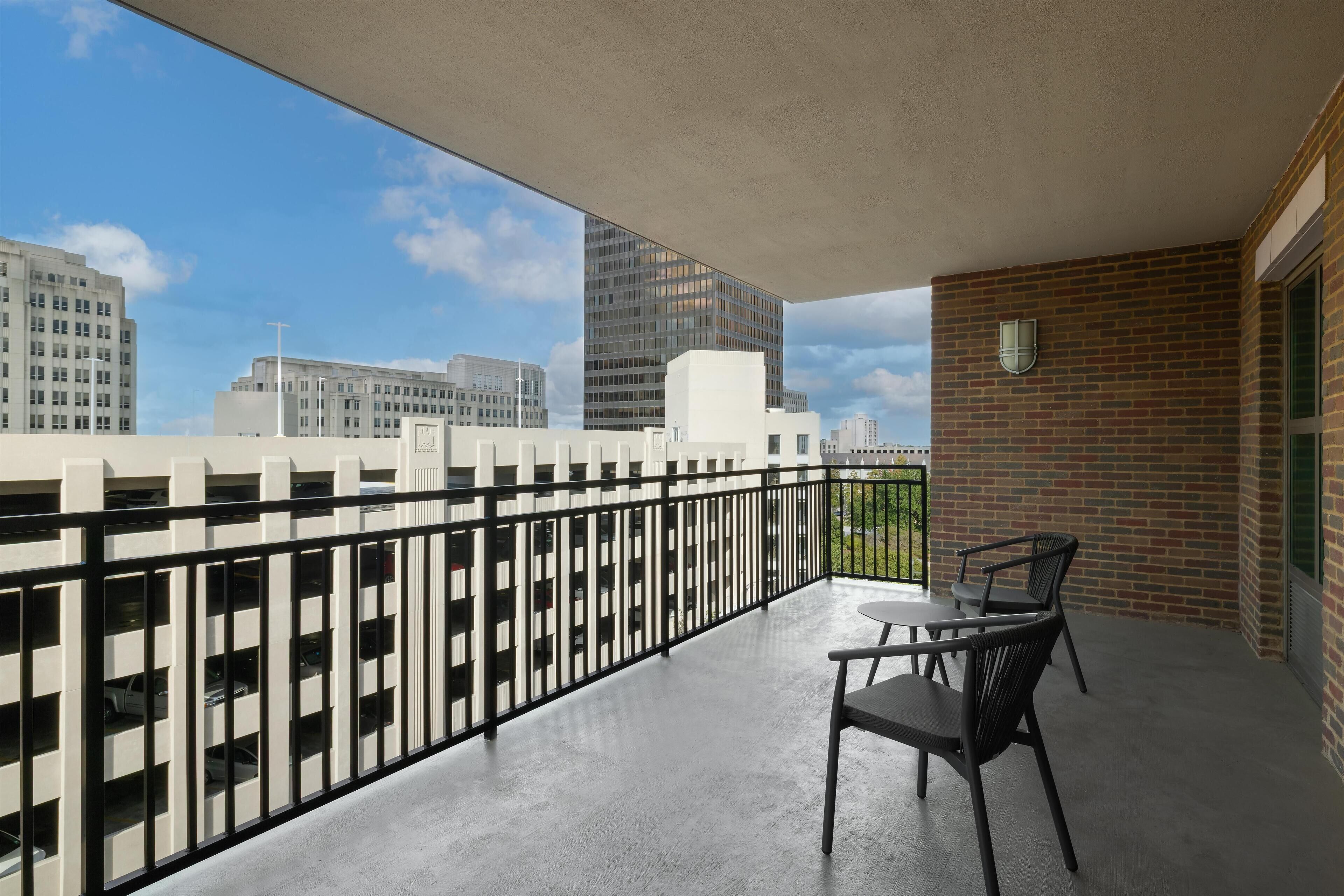 A balcony with a view of city buildings, a brick wall, and a table with chairs.