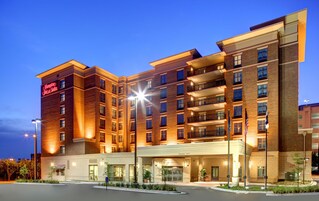 Un hotel de varios pisos con fachada de ladrillo, entrada iluminada y cielo despejado.