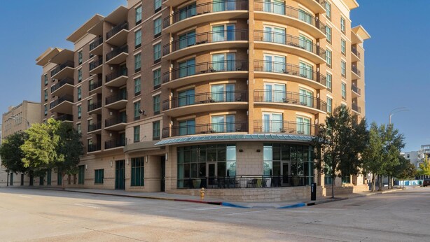 A multi-story hotel with a curved facade, balconies on each floor, and a clear sky.